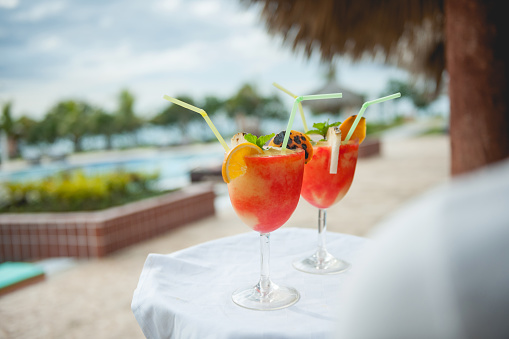 Waiter serving two tequila sunrise cocktail at hotel resort