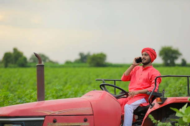 istock young indian farmer sitting on tractor and talking on smartphone at field 1280781977