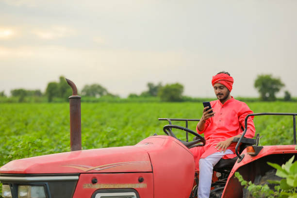 istock Indian farmer working with tractor and Using smartphone at field 1280782172
