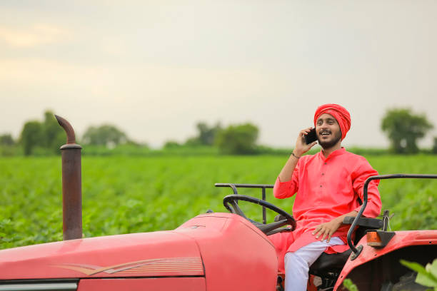 istock young indian farmer sitting on tractor and talking on smartphone at field 1280782277