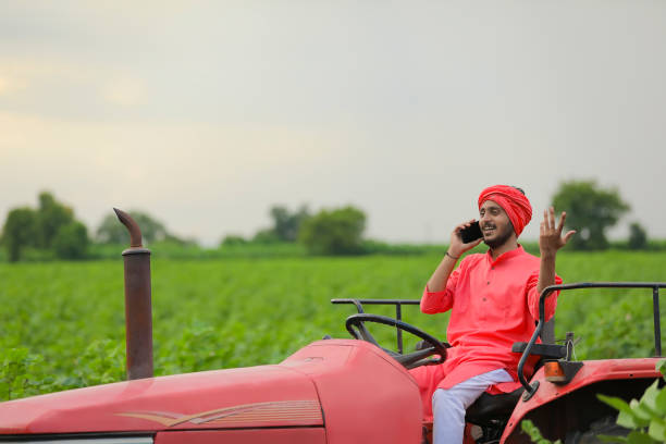 istock young indian farmer sitting on tractor and talking on smartphone at field 1280782326