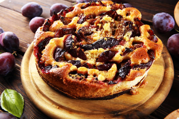 istock Rustic plum cake on wooden background with plums around. 1280787321