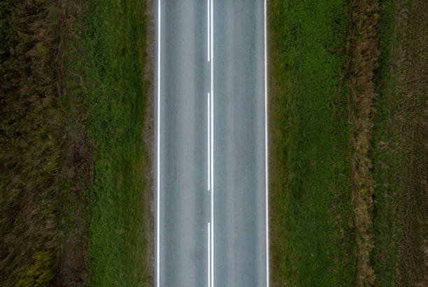 istock An asphalt road with a continuous lane on one side and a dividing strip on the other. View from above. 1280790847