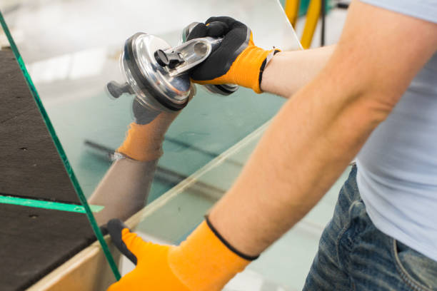 o glazier usa um para janelas. oficina de fabricação de vidro, o homem levanta o painel de vidro grosso sobre a mesa com a ajuda de ferramentas especializadas - window human hand through frame - fotografias e filmes do acervo