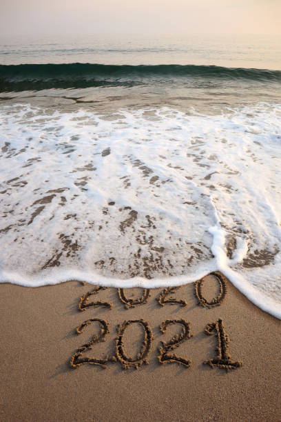 istock New year 2021 and 2020 on sandy beach with waves 1280791082