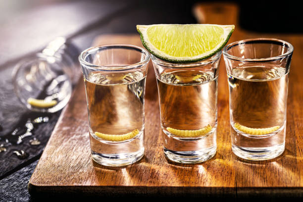 メスカル(またはメスカル)のいくつかのグラス、メキシコからの典型的でエキゾチックなブランデー、背景に幼虫とレモン - drink mexican culture tequila shot tequila ストックフォトと画像