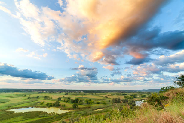 A beautiful valley with a river, blue sky with large clouds and bright sun. Aerial 4K UHD.