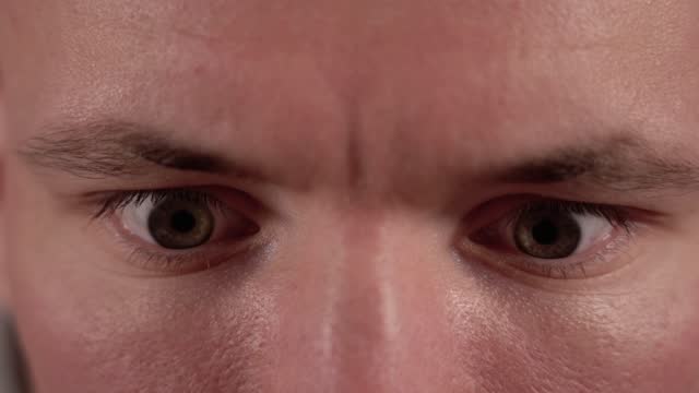 Emotional man with brown eyes and moving fast pupils closeup
