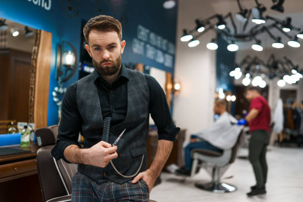 istock Brutal barber master with scissors and a comb in hands 1280808962