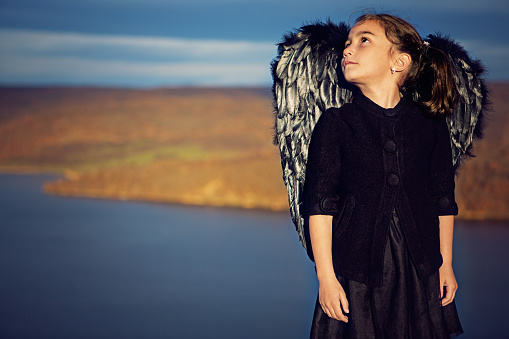 Portrait of little girl dressed like a black angel