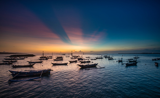 Colorful sunset with numerous local fishing boats situated at Jimbaran bay in Bali Indonesia.