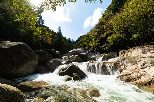 A pristine mountain stream with waterfalls flowing down a valley on a sunny day.