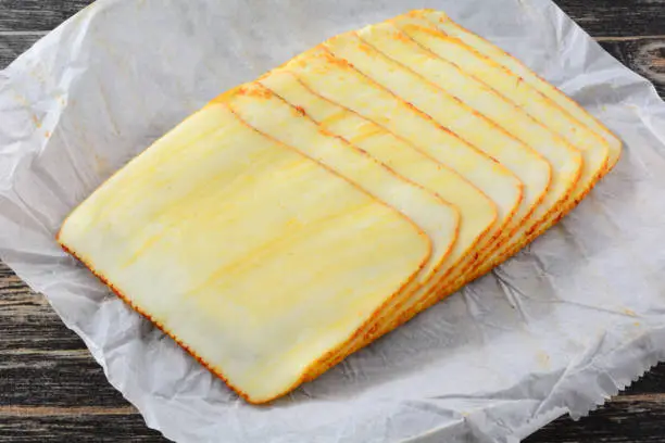 Stack of muenster cheese slices on white paper butcher paper
