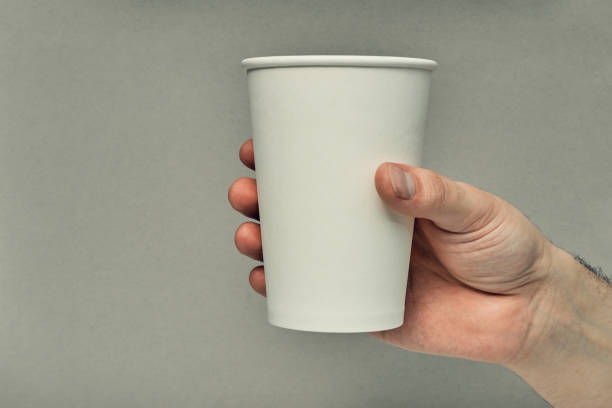 istock Paper cup in hand on a colored background. Eco-friendly materials in a coffee shop, biodegradable disposable tableware. Close up 1280814369