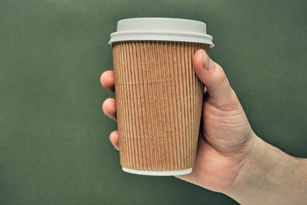 istock Paper cup in hand on a colored background. Eco-friendly materials in a coffee shop, biodegradable disposable tableware. Close up 1280814374
