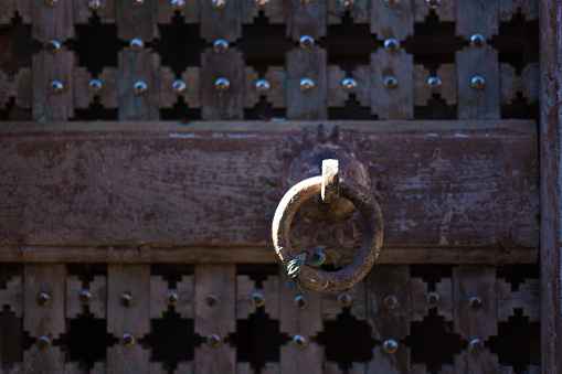 Detail from an ornate antique distressed wooden Indian door with door pull.