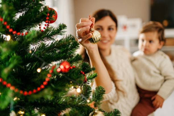 istock Young mom with baby boy decorating Christmas tree 1280821272