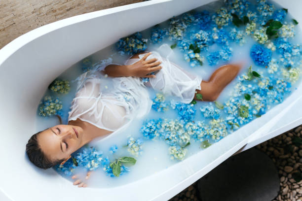 열대 파란색 수국으로 목욕을 즐기는 여성. - bathtub women naked human face 뉴스 사진 이미지