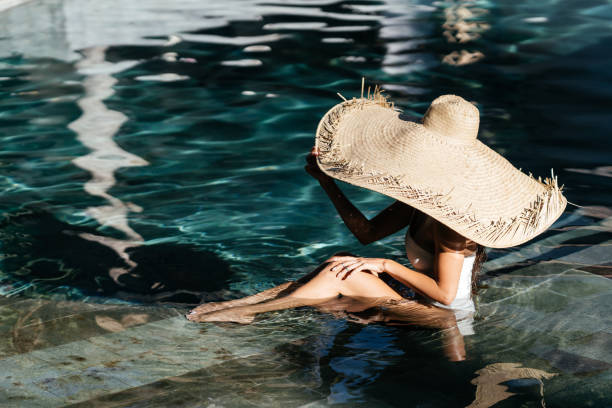istock Woman in big straw hat relaxing at pool. 1280840420