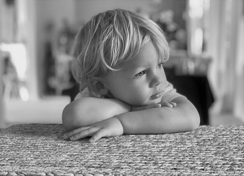 Thinking toddler boy leaning on his arms