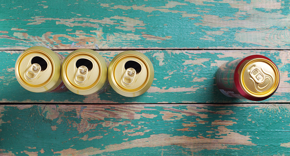 Opened beer cans on old green wooden background, top view