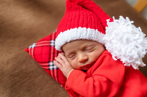 Cute newborn baby in Santa hat. Sleeping baby on a dark background. Closeup portrait of newborn baby. Baby goods packing template. Nursery. Medical and healthy concept. Christmas. New Year