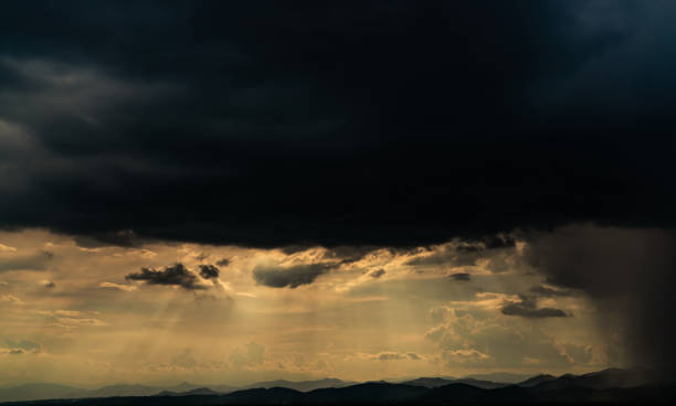 Heaven sky with god light over mountain range. Sun rays through dark clouds. Stormy sky. Golden sunlight shine from heaven sky for hope and faithful. Landscape of mountain layer. Beauty in nature.