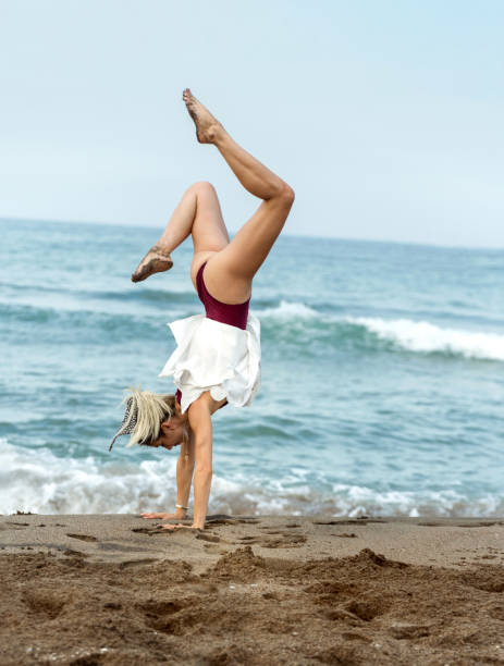 istock Young woman practicing handstand on the beach 1280856010