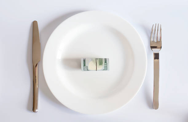 istock A dollar bill on a white plate between a fork and a knife on white background, 1280856188