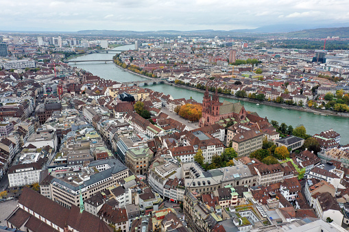 Basel with the river rhine. In the background visible the Novartis Campus with several laboratories and factories. In the foreground the old town with the Minster of Basel. The  wide angle image was captured during autumn season.