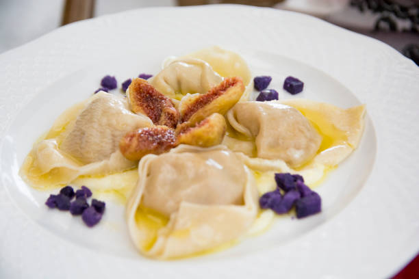 Ravioli with ricotta cheese, figs and purple sweet potatoes, served in a white plate, Italy Ravioli with ricotta cheese, figs and purple sweet potatoes, served in a white plate, Italy mezzaluna stock pictures, royalty-free photos & images