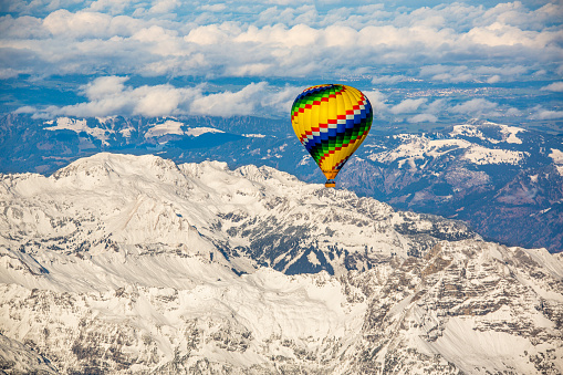 Balloons burning fuel as they fly over the city of Goreme in Cappadocia, with sightseeing tourists during a sunny summer day