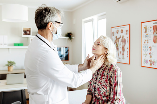 Shot of a mature male doctor examining a senior female patient in his medical office