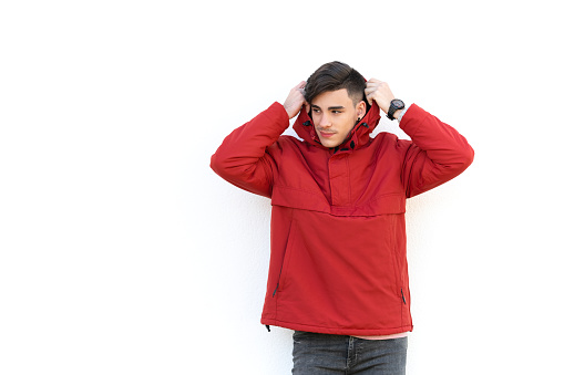 young man in red coat over white wall