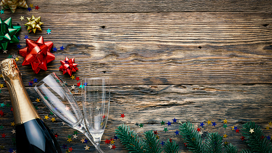 Christmas wooden background, champagne, glasses, fluffy fir branches and festive decor, copy space for text, top view
