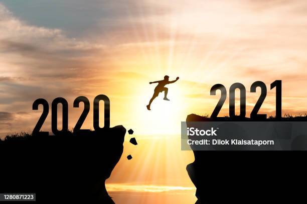 Welcome Merry Christmas And Happy New Year In 2021silhouette Man Jumping From 2020 Cliff To 2021 Cliff With Cloud Sky And Sunlight Stock Photo - Download Image Now