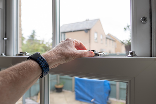 Shallow focus of an adult seen unlocking a newly installed double glazed window in a kitchen.