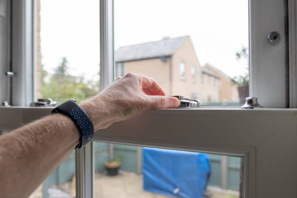 Shallow focus of an adult seen unlocking a newly installed double glazed window in a kitchen. stock photo