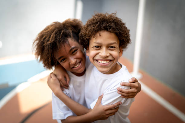 retrato de amigos abraçados na quadra de esportes da escola - fun simplicity children only color image - fotografias e filmes do acervo