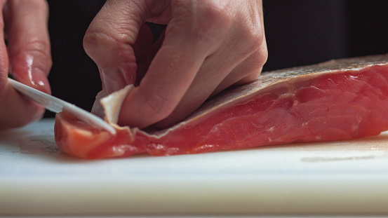Sushi Chef Slices fresh Salmon on the sushi bar. A sushi-man slicing a salmon steak with his Japanese knife. Preparing sushi nigiri fish. Japanese cuisine recipes