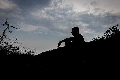 Man sitting shadow with blue sky background showing the state of loneliness