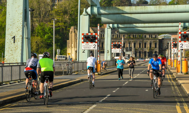 Senior male bicyclist in yellow jersey riding old railroad bridge converted into recreation trail; Missouri River on the left; autumn in Missouri