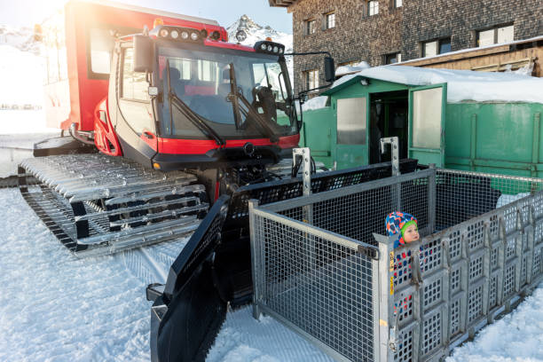 lindo adorable juguetón feliz niño dentro de rojo moderno snowcat ratrack snowplow box grooming de pie en la estación de esquí alpino pico ischgl austria. maquinaria pesada equipo de montaña vehículo de pista - box little boys bright car fotografías e imágenes de stock