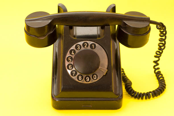 винтажный телефон в стиле ретро на желтом фоне. старый стационарный телефон с спиральным кабелем. - 1950s style telephone image created 1950s rotary phone стоковые фото и изображения