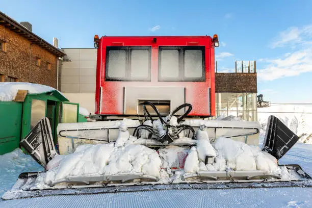 Rear back door window view covered with snow after blizzard snowfall of red modern snowcat ratrack grooming machine after preparing ski slope piste alpine skiing resort. Human face likeness illusion.