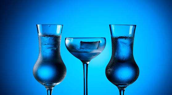 Strong alcoholic drink in frozen glasses with ice. Frozen glasses on a blue background.