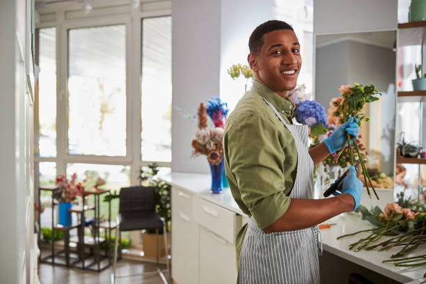 istock Smiling young man working in flower shop 1280894998