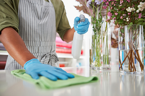 Shop assistant cleaning surfaces in flower shop