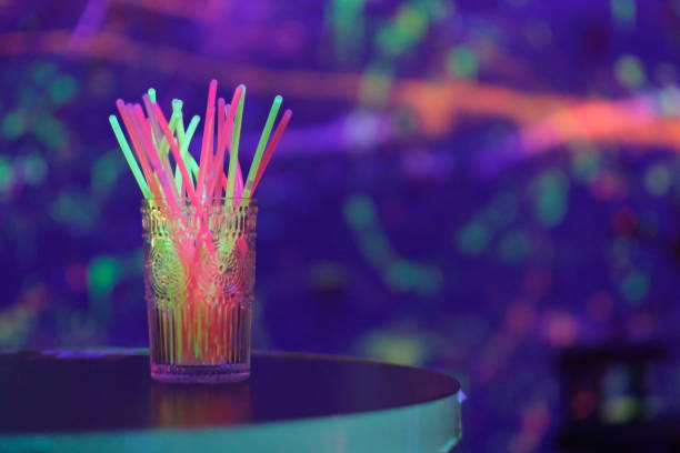 colorful light sticks on bar table. Colorful bokeh background close up glass of colorful light sticks on bar table. Colorful bokeh background glow stick stock pictures, royalty-free photos & images