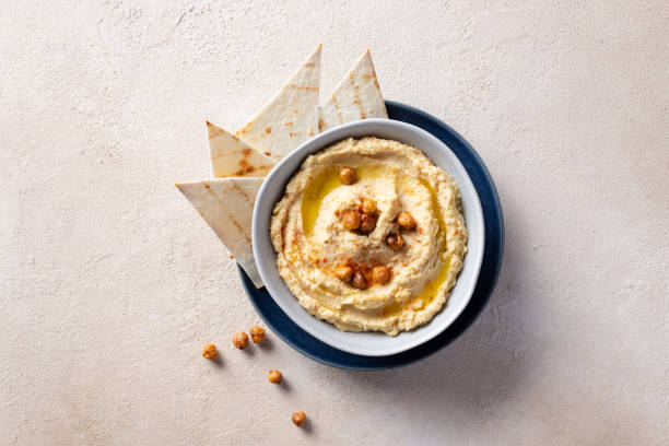 istock Hummus, chickpea dip in ceramic bowl over beige textured background 1280908225